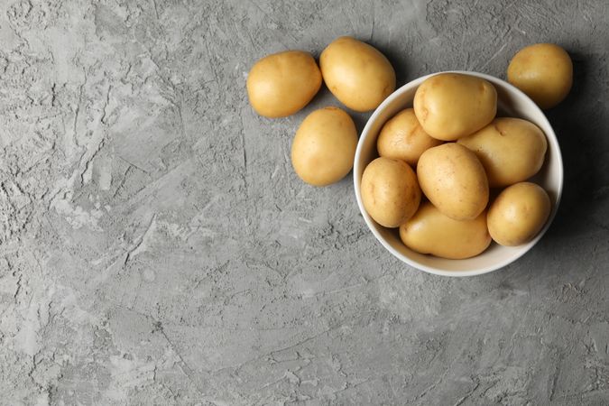 Top view of fresh potatoes in ceramic bowl, copy space
