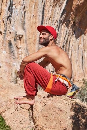 Smiling male alpinist sitting on boulder