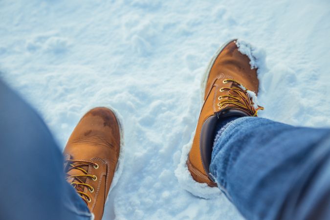 Man legs in winter boots on snow near mountains