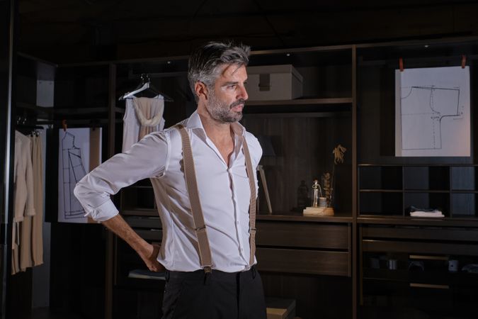 Unshaven stylish man trying on suspenders