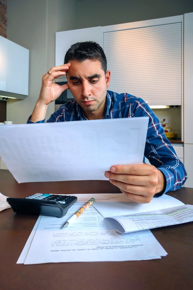 Man reviewing bills at kitchen counter