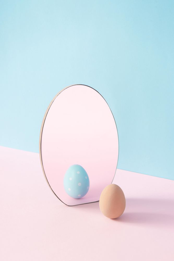 Egg and mirror on pastel pink and blue background