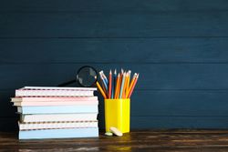 Composition with school supplies on wood table against dark background