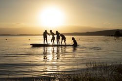 Silhouette of boys standing on surfboard at sunset