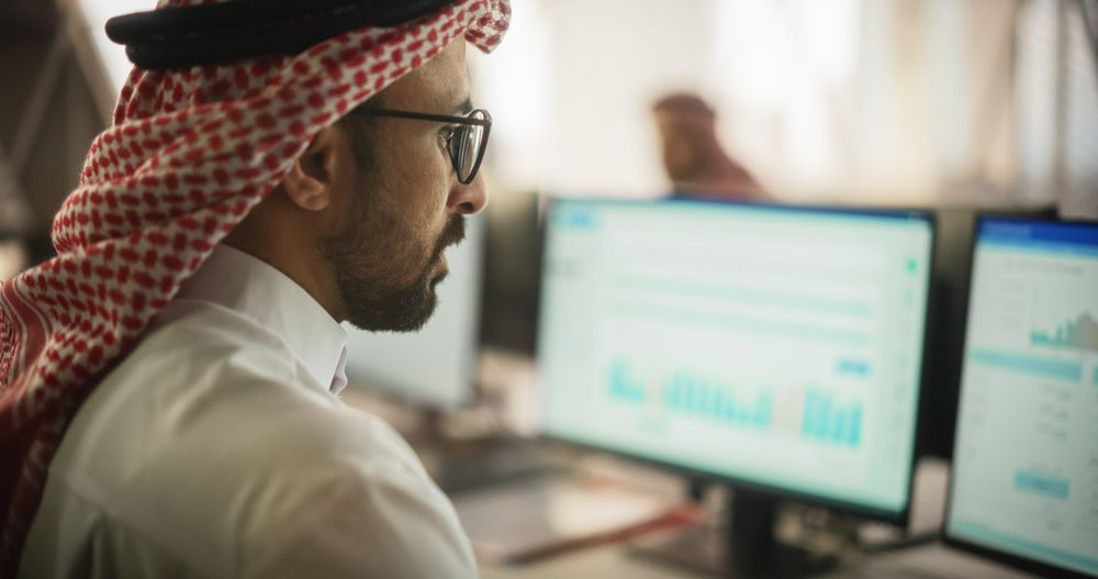 Portrait of a Middle Eastern Financial Securities Trader Working on Desktop Computer in a Modern Office.