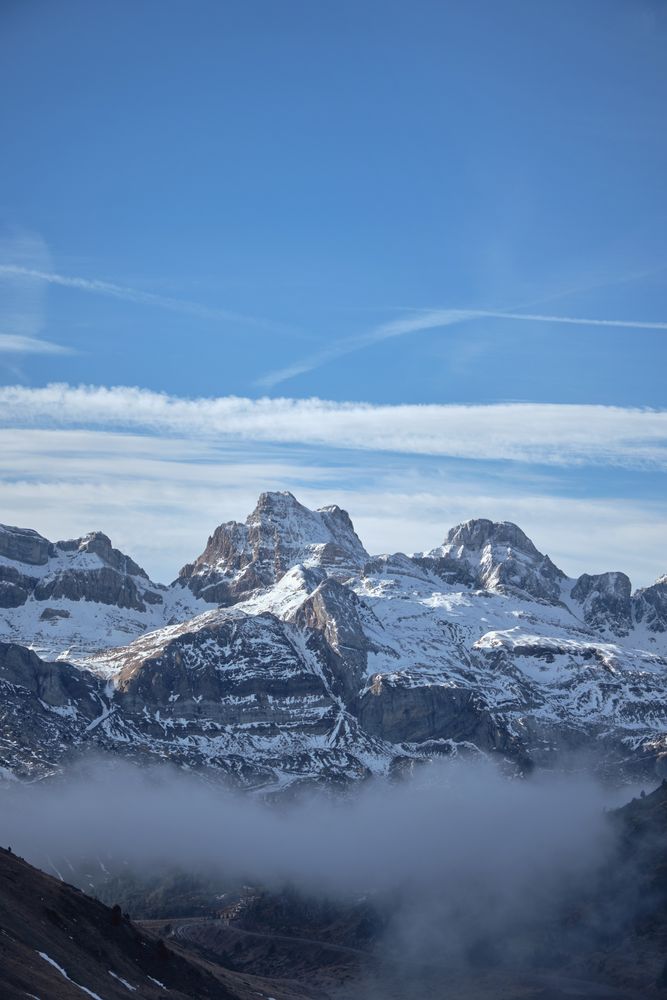 Snowy mountains and mist against blue sky
