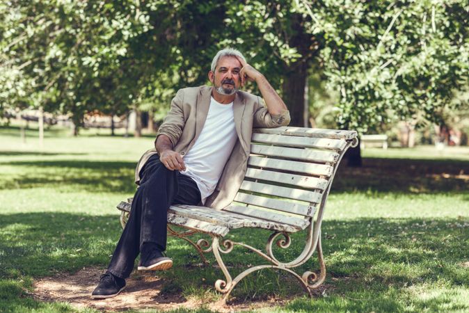 Portrait of a mature man, sitting on bench in a park