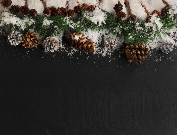 Christmas top border on dark stone with snow  plus silver gold pine cones