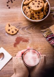 Female hands with hot drink and chocolate cookies