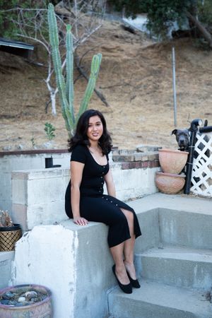 Beautiful woman sitting on cement steps with her dog peeking behind