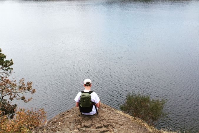 Back of man sitting on edge of lake