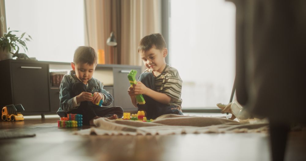 Portrait of Two Male Asian Kids Playing with Colorful Building Blocks in Their Room During the Sunny Day.