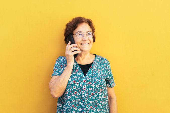 Cheerful older woman on a call outdoors
