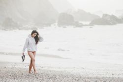 Woman walking on shore near stones and water