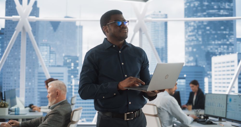 Black Man Using Laptop Computer To Go Through Tasks And Business Mettings In Hedge Fund.