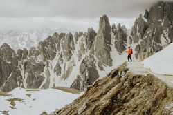 Man on hill near snow covered mountains