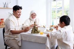 Young Asian Muslim Family , Father, Mother, and Two Kids Eat Ketupat Lebaran Together,