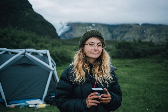 Woman with warm drink in front of tent