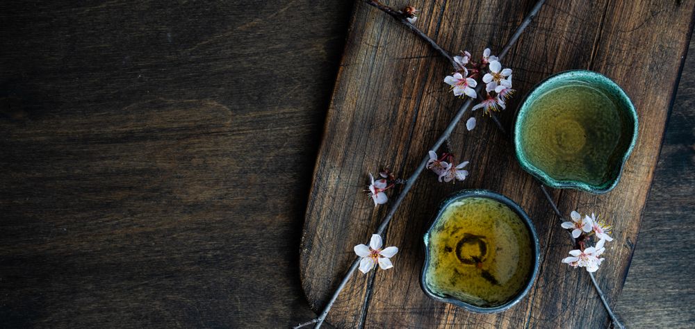 Green tea in cups and blooming peach tree branch garnish with copy space