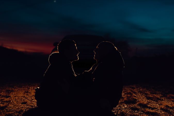 Men hugging and sitting on ground on field at night