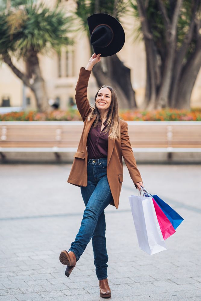 Joyful stylish woman enjoying shopping at city street