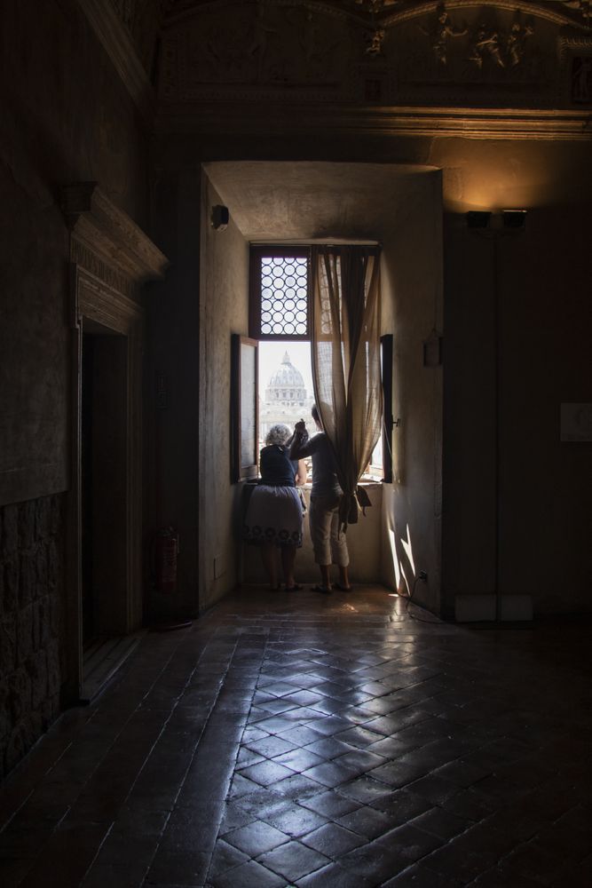 Back view of two people standing at the window in a dark room