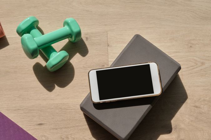 Smartphone placed near dumbbells on floor