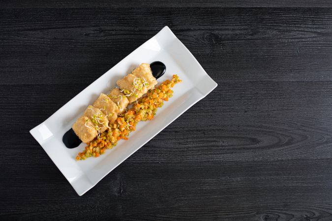 Hake breaded with matignon in white rectangular plate