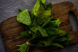 Fresh spinach wrapped on breadboard