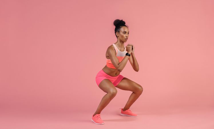 Sporty woman practicing squat exercises in studio