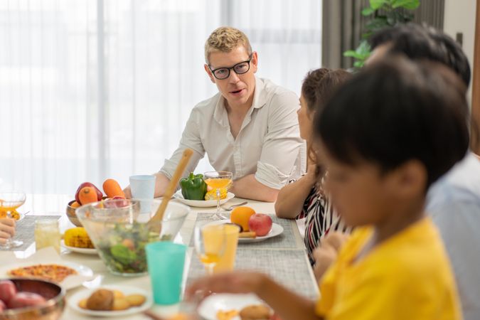 White couple having dinner with Asian family