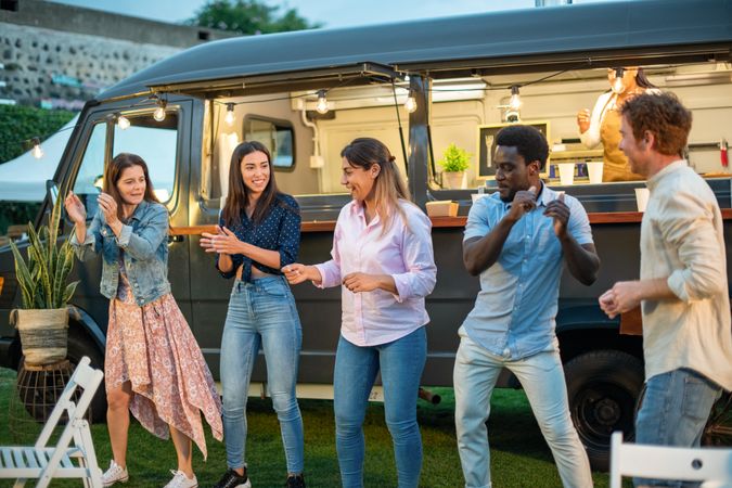 Happy diverse friends having fun near van