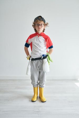 Boy wearing superhero costume with cleaning tools