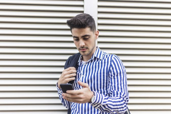 Young man standing outdoors and checking phone