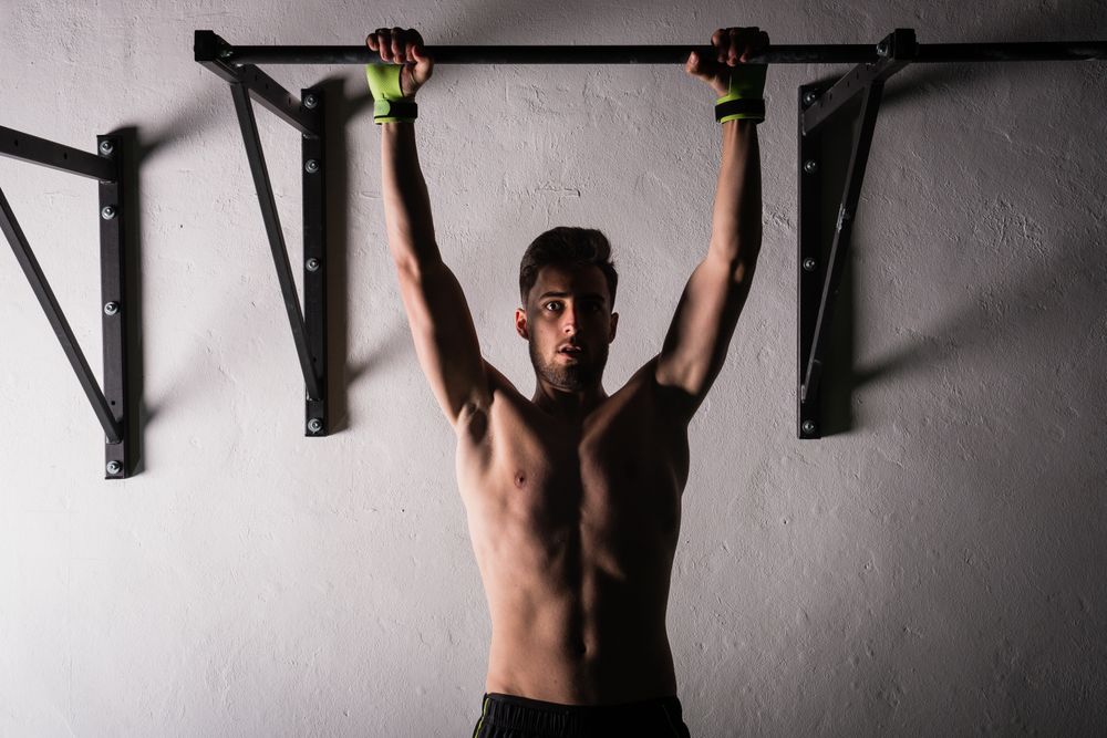 Man hanging on bar near wall in gym