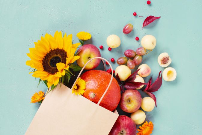 Craft paper bag with fresh autumn fruits and vegetables, decorated with flowers