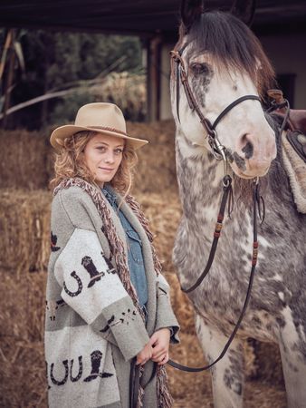 Adult female equestrian holding purebred horse by reins