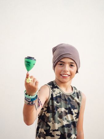 Smiling boy spinning tops on finger and looking at camera
