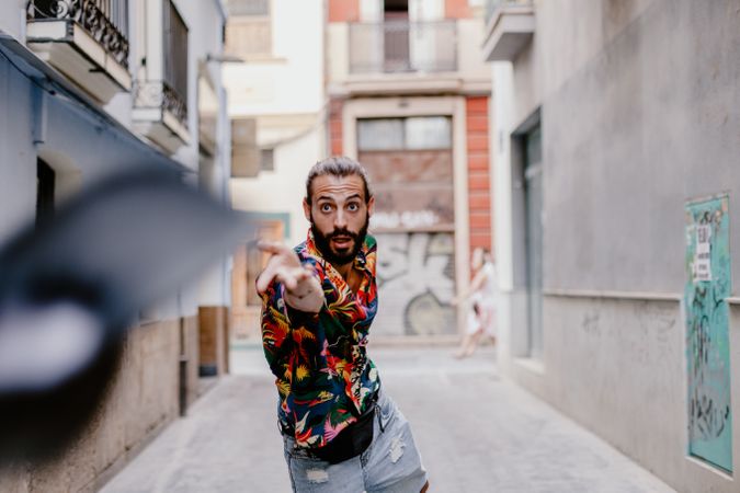 Young man throwing cap on alley