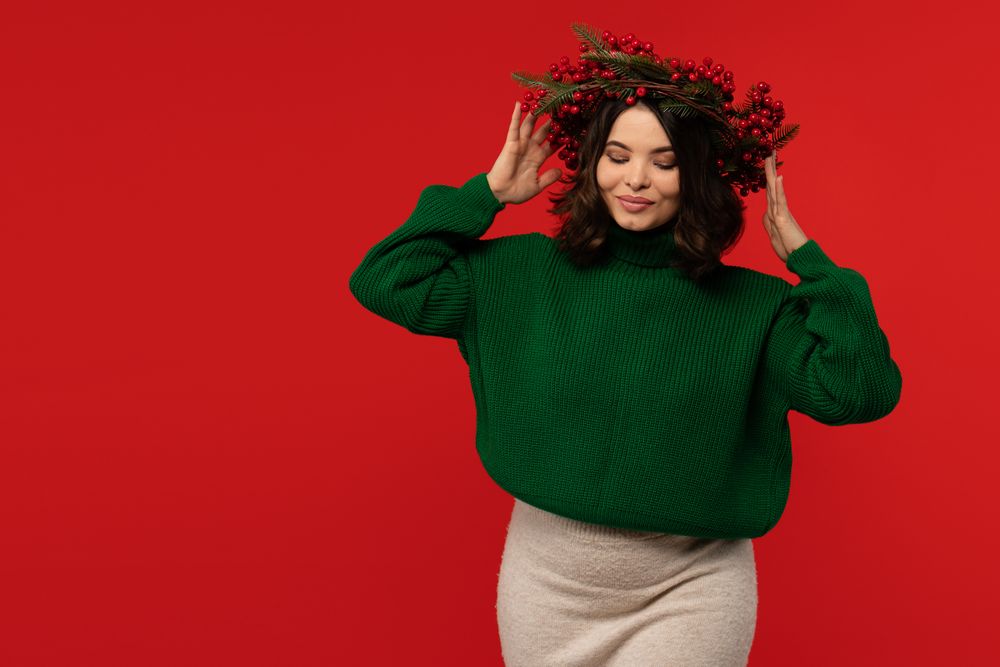 Woman wearing festive wreath of red berries and pine branches.