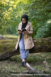 Middle Eastern woman leaning on tree while reading 416Ojb