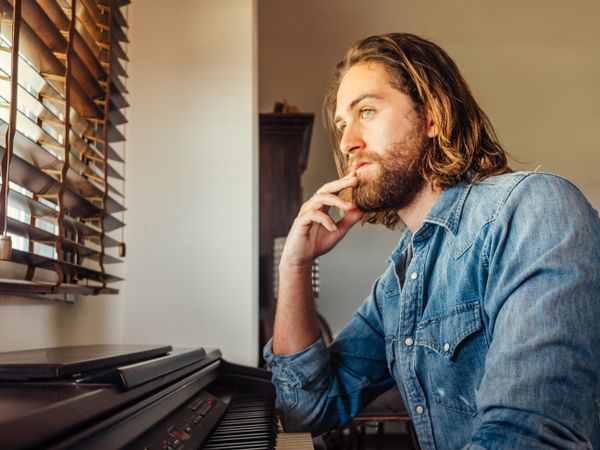 Thoughtful male playing synthesizer at home