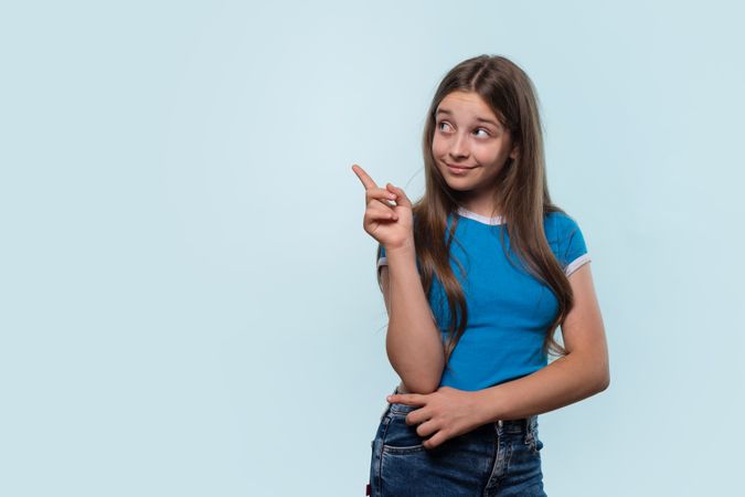 Young girl gestures with finger, looking thoughtful.