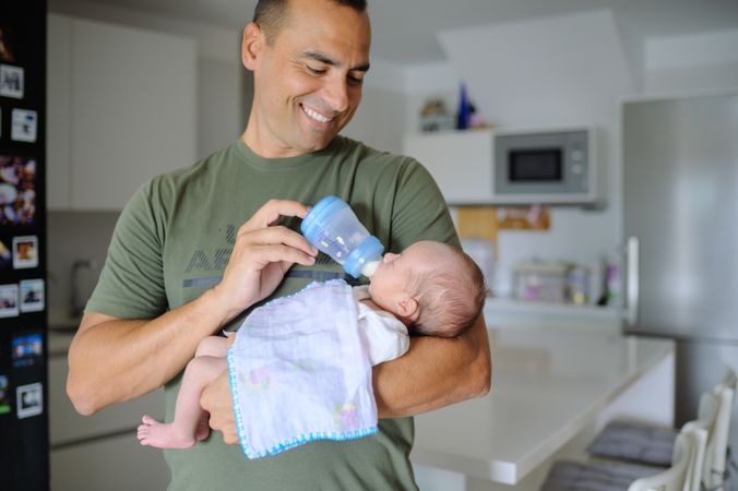 A man holding a baby in a kitchen