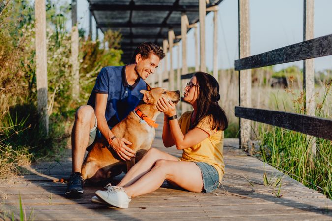 Happy adult couple having fun with dog at countryside