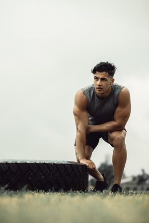 Fit young man doing a tire flip workout outdoors