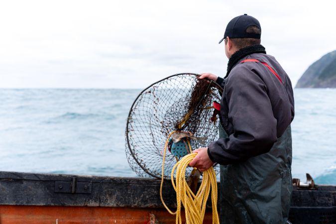 Fisherman picking up a container with nets for fishing