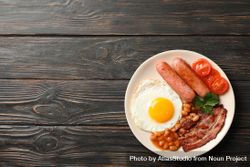 Top view of fried breakfast with eggs, bacon and sausage on table, copy space bEZKG0