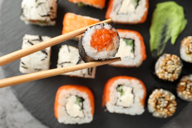 Chopsticks with delicious sushi roll, close up. Japanese food