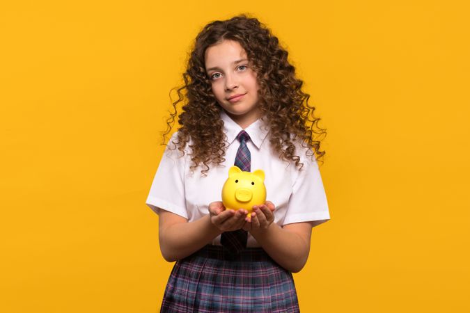 Girl holding a yellow piggy bank